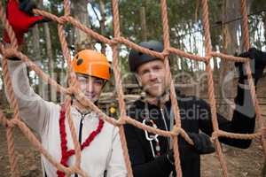 Couple wearing safety helmet holding and posing through a rope fence