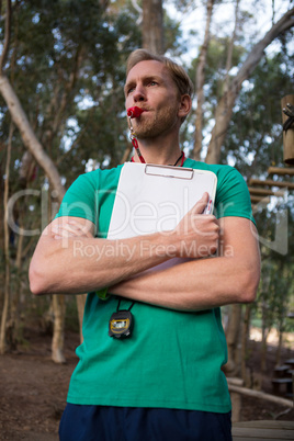 Athletic coach blowing whistle in the forest