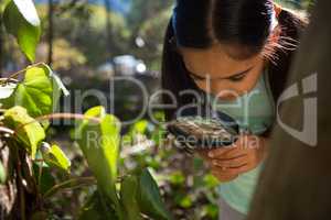 Little girl exploring nature through magnifying glass on a sunny day