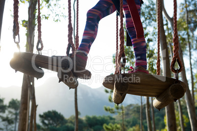 Little girl feet crossing obstacle in forest on a sunny day