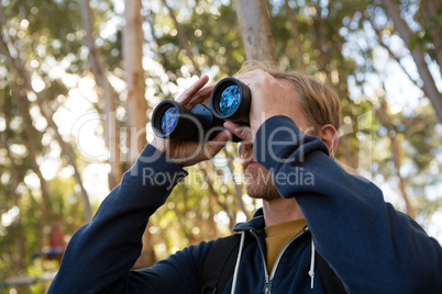 Man hiker exploring nature through binoculars