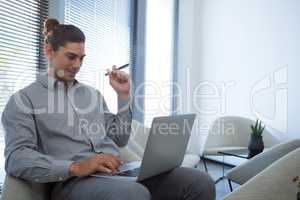 Male executive using laptop in waiting area