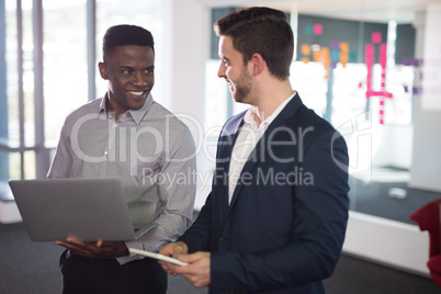 Happy male executives using laptop and digital tablet