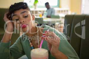 Woman keeping her head on hand while looking at milkshake
