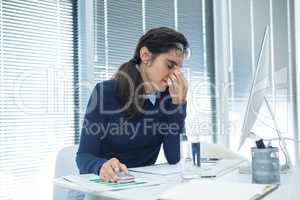 Tired female executive sitting at desk