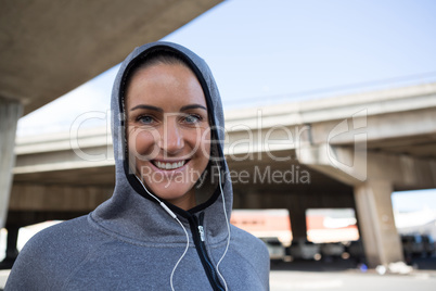 Smiling woman in hoodie listening to music on headphones