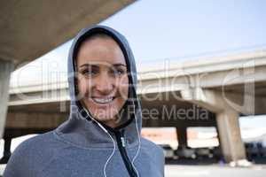 Smiling woman in hoodie listening to music on headphones
