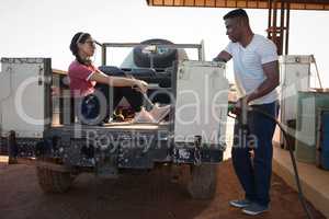 Man filling petrol while woman sitting in car