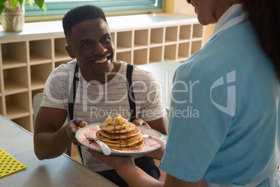 Waitress serving breakfast to man