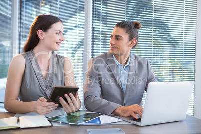 Business executives using laptop and digital tablet at desk