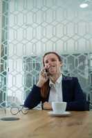 Female executive talking on mobile phone at desk