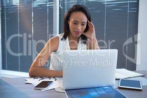 Female executive using laptop at desk