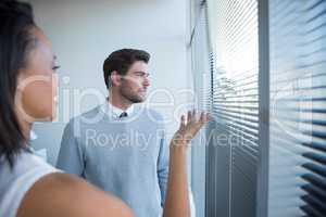 Male and female executives interacting while looking through window