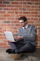 Executive using laptop against brick wall