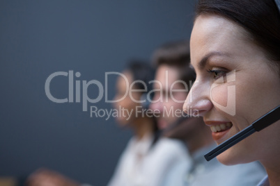 Female executive with headset using computer at desk