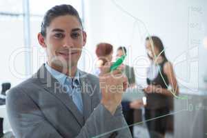 Confident male executive holding marker and looking at camera