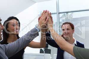 Group of executives giving high five at office