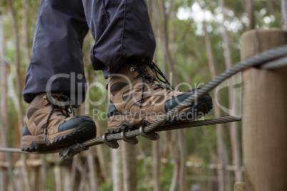Hiker foot walking on zip line cable in the forest
