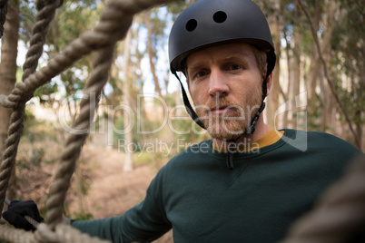 Portrait of hiker man posing through a rope fence in the forest