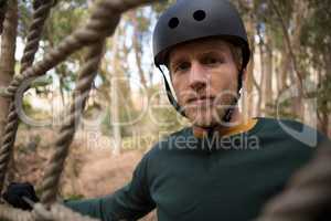 Portrait of hiker man posing through a rope fence in the forest
