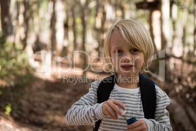 Little girl holding bubble wand in her hand in the forest on a sunny day
