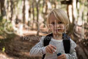Little girl holding bubble wand in her hand in the forest on a sunny day