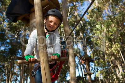 Little girl wearing helmet lining on wooden ladder