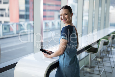 Portrait of happy female executive using mobile phone