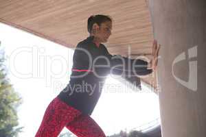 Fit woman doing stretching exercise with support of pillar