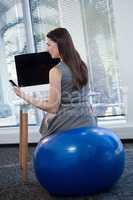 Female executive sitting on exercise ball while working at desk