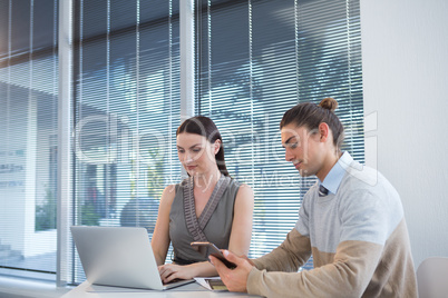 Business executives using laptop and digital tablet at desk