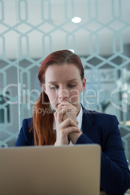 Thoughtful businesswoman using laptop at desk