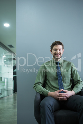 Smiling executive sitting on chair in waiting area