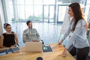 Female executive giving presentation to her colleagues in conference room
