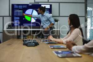 Male executive giving presentation to his colleagues in conference room