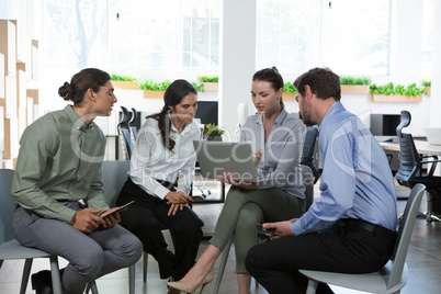 Group of executives discussing over laptop