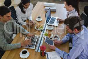 Group of executives discussing with laptop and snack at desk