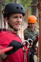 Smiling young man wearing safety helmet holding zip line cable in the forest