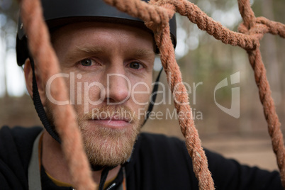 Portrait of man posing through a rope fence in the forest