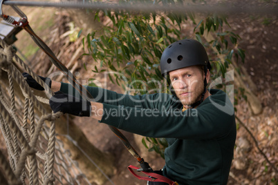 Male hiker wearing helmet climbing rope fence