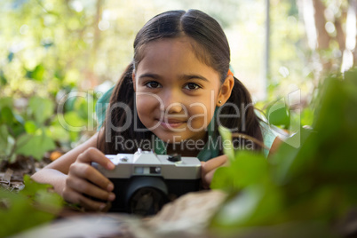 Little girl lying on floor holding camera in her hand on a sunny day
