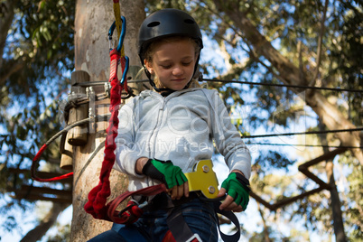 Little girl wearing helmet trying to fix her harness