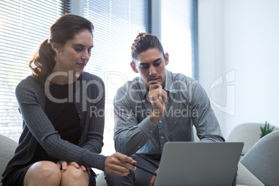 Colleagues discussing over laptop in waiting area