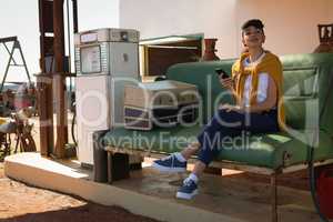 Woman using mobile phone at petrol pump station