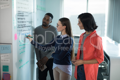 Male and female executives writing on whiteboard