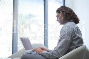 Male executive using laptop in waiting area