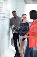 Male and female executives discussing on whiteboard