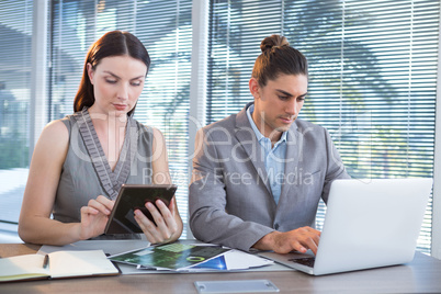 Business executives using laptop and digital tablet at desk