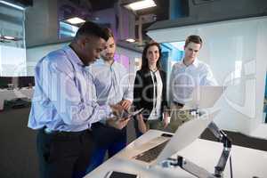 Executives discussing over laptop and digital tablet