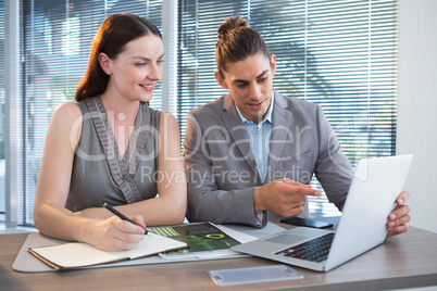 Business executives discussing over laptop at desk